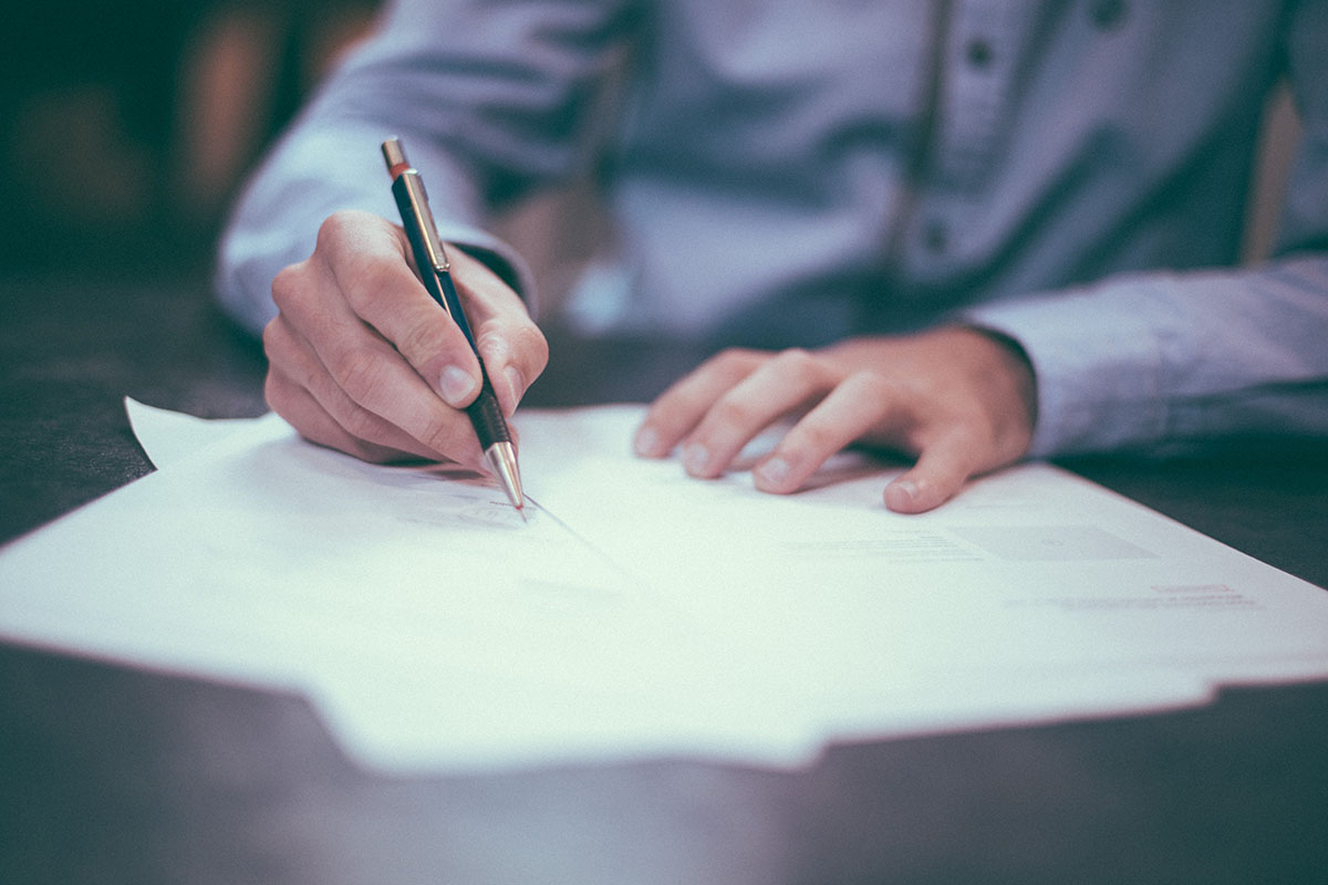 man writing on legal document